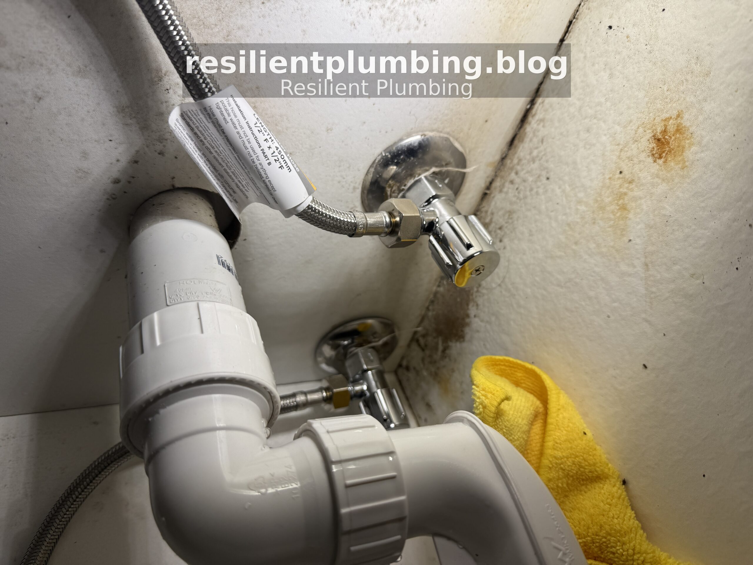 Plumber installing quarter-turn isolation valve under kitchen sink cabinet in Melbourne