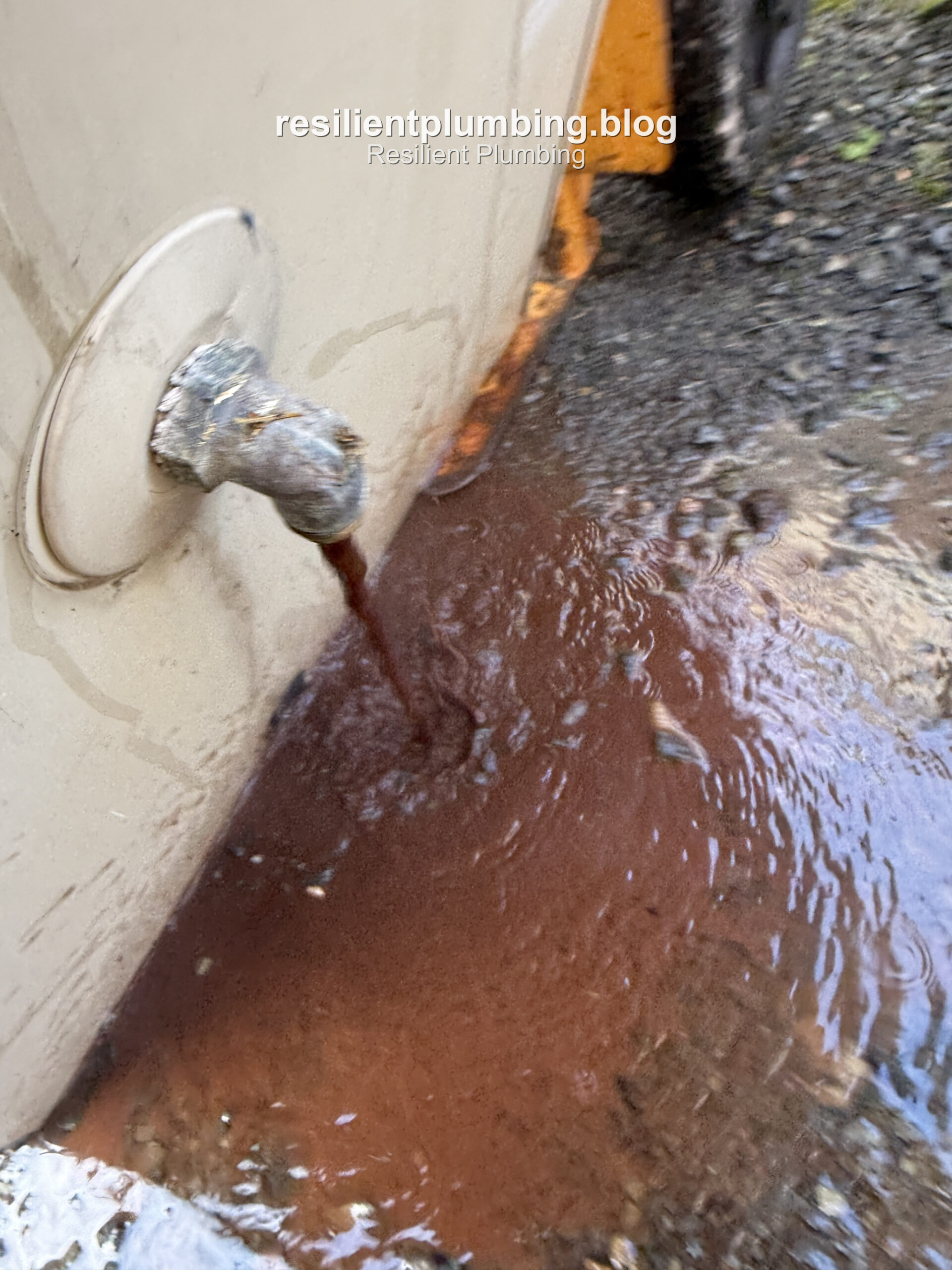 Rust-coloured water draining from an old hot water unit