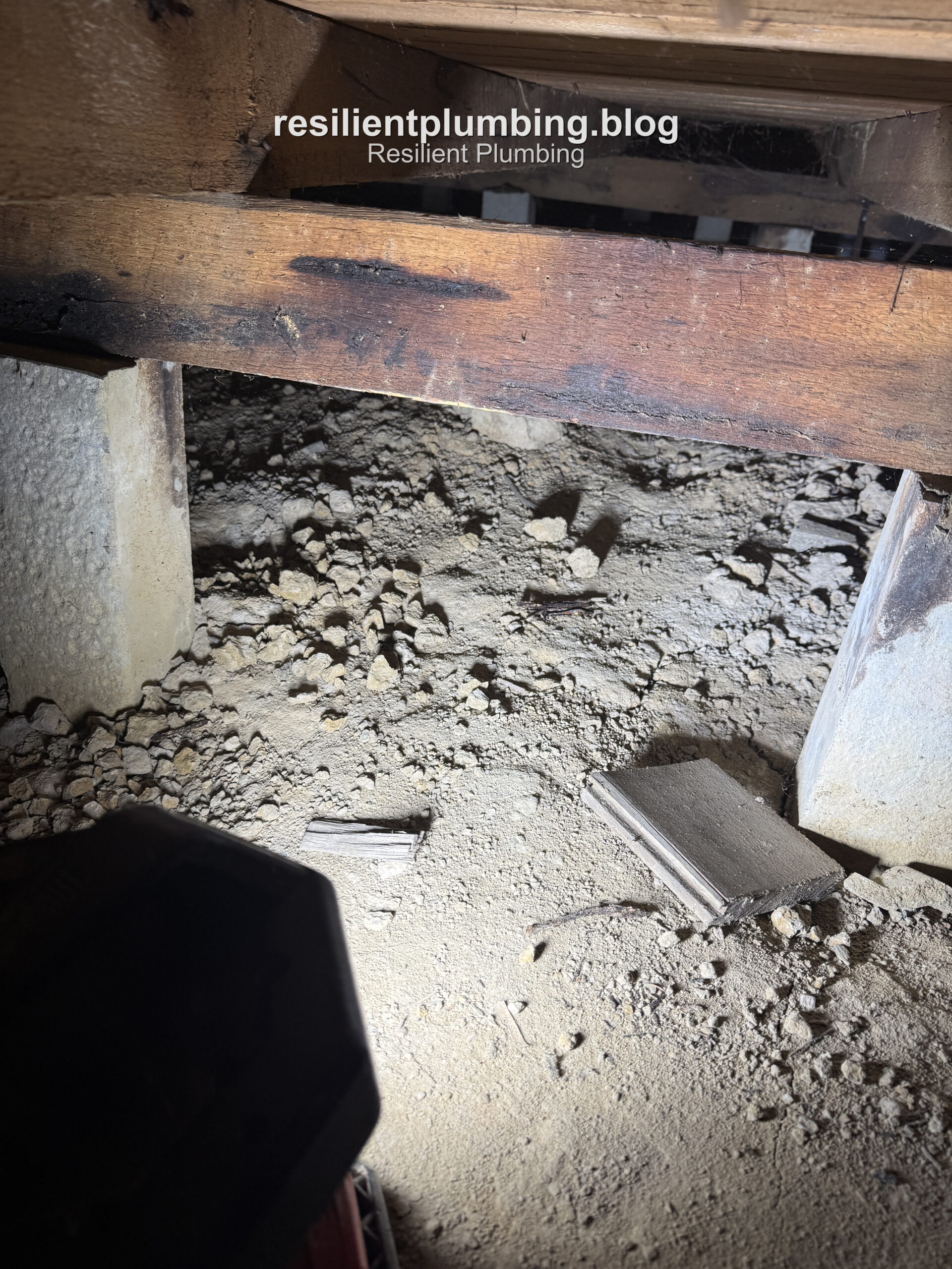 Wider view of the low-clearance subfloor showing framing and services