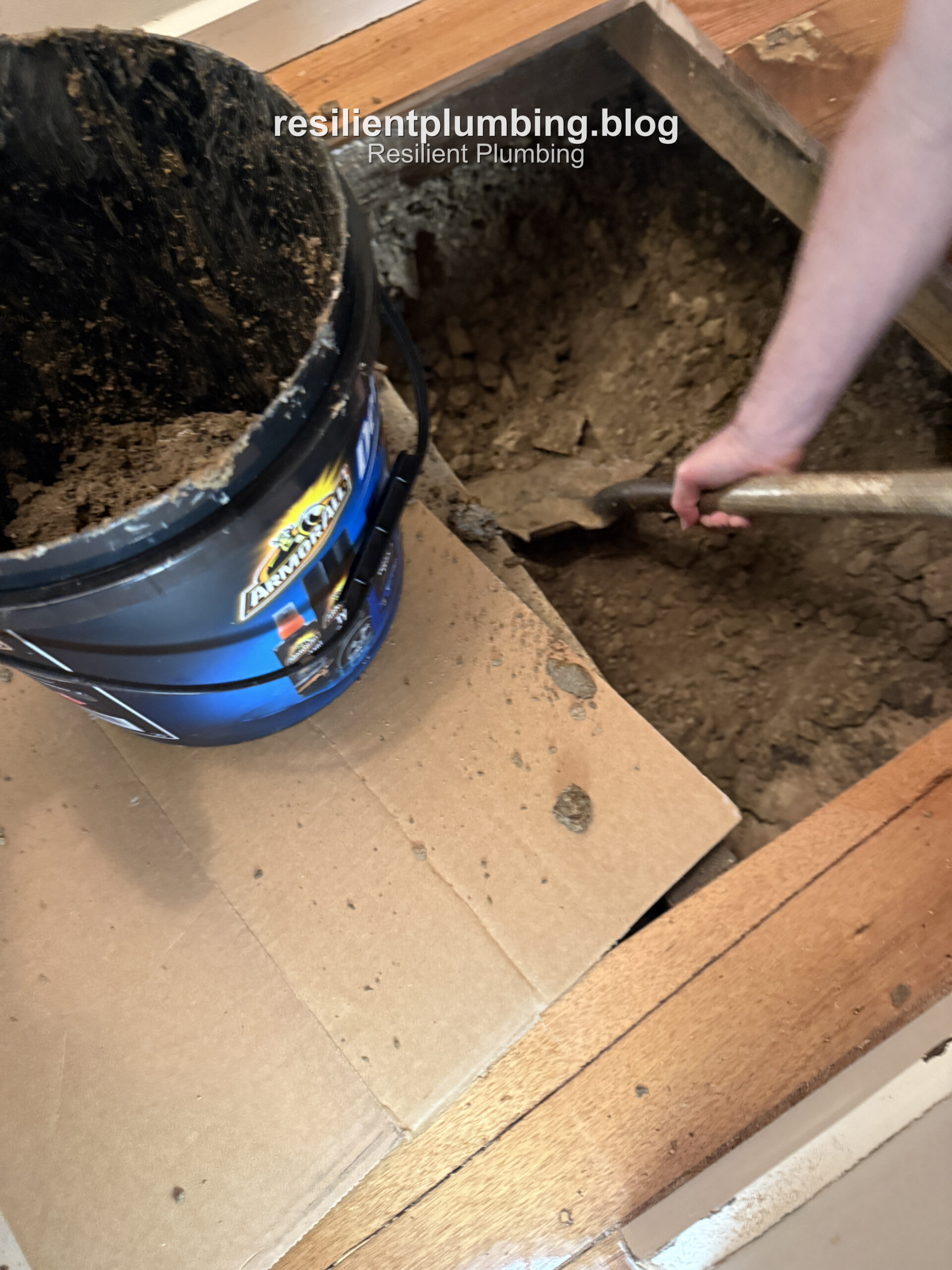 Digging out wet soil around the pipe with cardboard laid down to catch mud